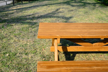 Fototapeta premium Empty wooden picnic table with bench in park on sunny day
