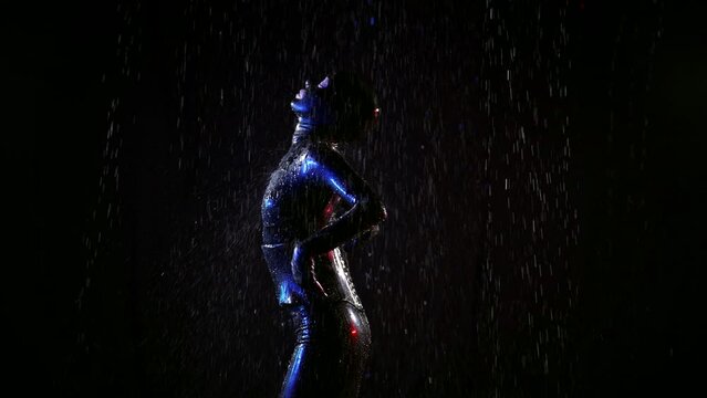 Fetish fantasy with bdsm role play, a woman in a black latex suit dancing in the dark in streams of water