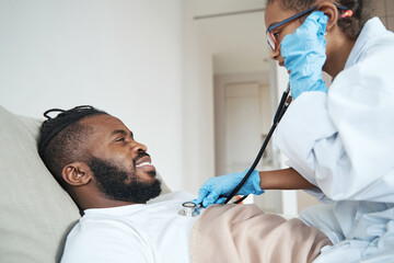 Girl in a medical gown listens to breath of father with stethoscope