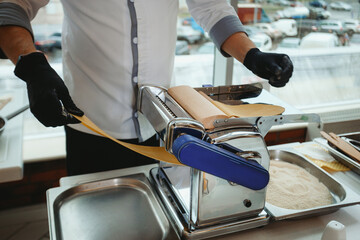 chef in the restaurant making handmade pasta with cutting pasta machine