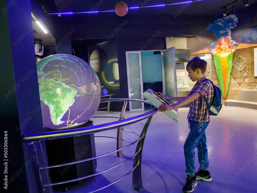 Wall mural yong school boy enjoy play and learn with science learning activities at the space and earth evoluti
