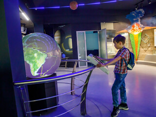 Yong school boy enjoy play and learn with science learning activities at the space and Earth evolution museum on weekends, Novosibirsk - Russia, 6 april 2022 - obrazy, fototapety, plakaty