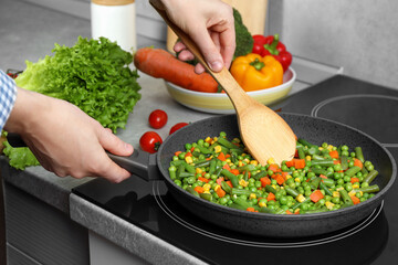 Woman cooking tasty vegetable mix in frying pan at home, closeup