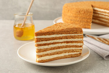 Fototapeta na wymiar Slice of delicious layered honey cake served on grey table, closeup