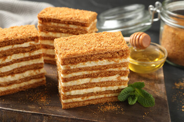 Fototapeta na wymiar Delicious layered honey cake on wooden board, closeup