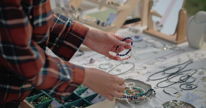 Girl`s hands choosing the handmade jewellery  on the local fair outside. Shallow depth of field, shallow focus. Hand held