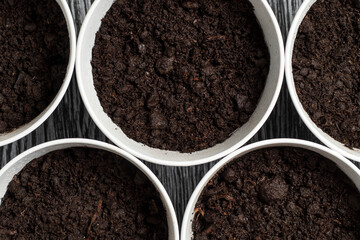 Potted soil with peat in metal pots. Growing greens or flowers at home concept.