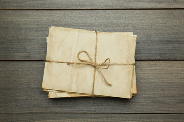 Stack of old letters tied with twine on wooden table, top view