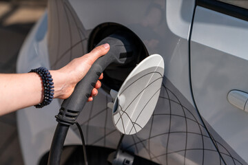 Woman holding plug of electric car charging station