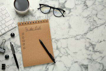 Flat lay composition with unfilled To Do list and cup of coffee on white marble table, space for...
