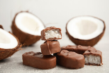 Delicious milk chocolate candy bars with coconut filling on grey table, closeup