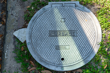 Vintage manhole cover marked "Garbage" near curb in Uptown New Orleans, LA, USA