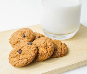 Chocolate chip cookies with glass of milk on wood plate and isolated white background. 