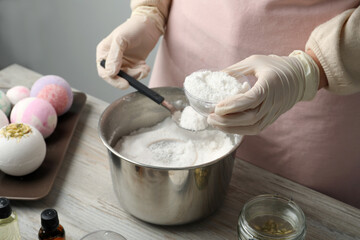Woman in gloves making bath bomb at wooden table, closeup