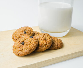 Chocolate chip cookies with glass of milk on wood plate and isolated white background. 