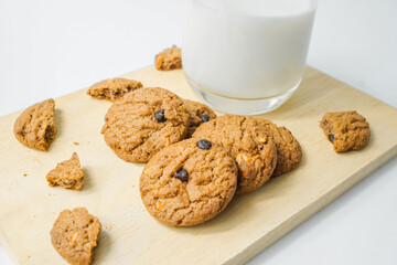 Chocolate chip cookies with glass of milk on wood plate and isolated white background. 