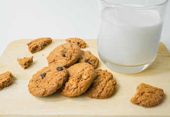 Chocolate chip cookies with glass of milk on wood plate and isolated white background. 