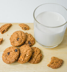 Chocolate chip cookies with glass of milk on wood plate and isolated white background. 