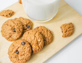 Chocolate chip cookies with glass of milk on wood plate and isolated white background. 