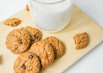 Chocolate chip cookies with glass of milk on wood plate and isolated white background. 
