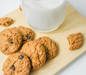 Chocolate chip cookies with glass of milk on wood plate and isolated white background. 