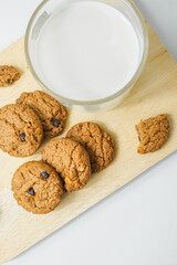 Chocolate chip cookies with glass of milk on wood plate and isolated white background. 