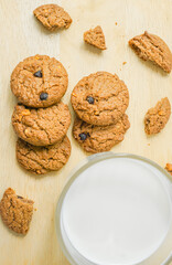 Chocolate chip cookies with glass of milk on wood plate and isolated white background. 