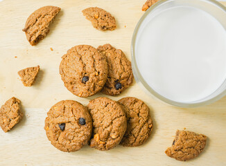 Chocolate chip cookies with glass of milk on wood plate and isolated white background. 