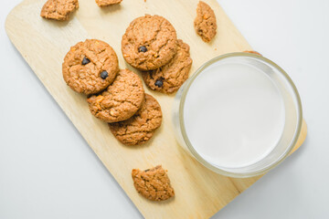 Chocolate chip cookies with glass of milk on wood plate and isolated white background. 