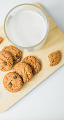 Chocolate chip cookies with glass of milk on wood plate and isolated white background. 