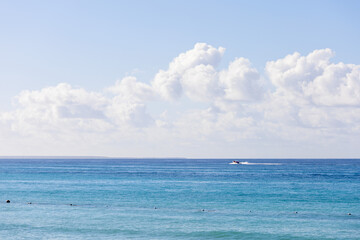 Obraz premium View of the Caribbean Sea in the Dominican Republic,the sea surface,the horizon and a small boat in the distance.Blue sky with clouds and ocean of beautiful color.Beautiful landscapes of the sea coast