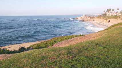 Ocean waves crashing on beach, sea water surface from above, eroded cliff of La Jolla shore, California pacific coast, USA. Seascape natural background. Erosion of bluff on coastline. Green grass lawn