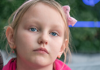 portrait of a little sad girl 7-8  years old blonde with blue eyes
 