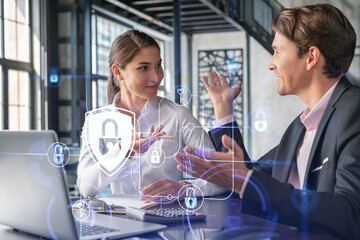 Obraz premium Businessman and businesswoman working together to protect clients confidential information and cyber security. IT hologram padlock icons over office background with panoramic windows.