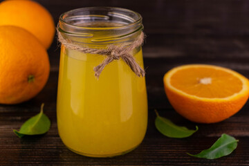 Freshly squeezed orange juice in a jar on a dark wooden background.