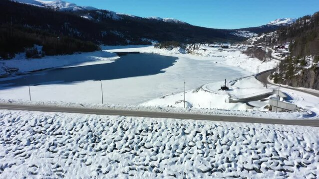 Aerial flying above Tunhovd dam and looking into Tunhovdfjorden water magazine with low fill grade during winter - Reservoir for Statkraft Nore powerplant in Rodberg