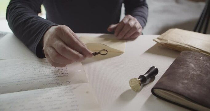 Man puts a key in an envelope with a letter. Camera slow dolly movement