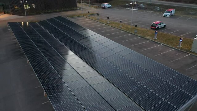 Rooftop of solar powered ev car charging station in Porsgrunn Norway - Hundreds of solar panels producing electricity for car charger - Evening ascending aerial with tilt down