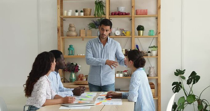 Confident male team leader ceo hold briefing explain plan idea project strategy to multicultural creative designers. Diverse department staff professional architects listen to boss on business meeting