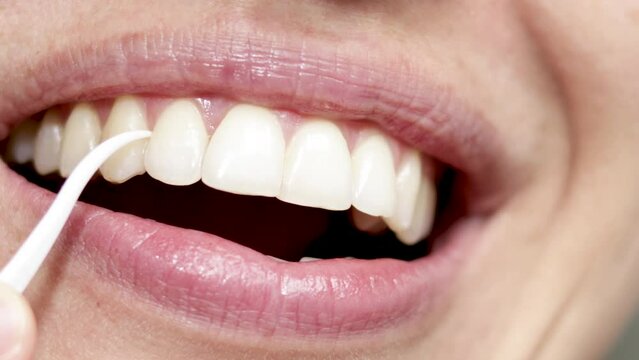 close up woman mouth, clean and floss space between teeth with plastic toothpick. smiling girl with beautiful natural teeth, sexy lips. dental oral hygiene, daily routine. dental floss