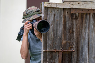 Female paparazzi detective taking pictures from the hide.