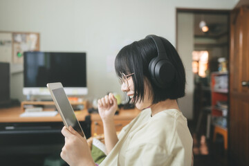 Young adult asian woman wear headphone listen music and relax using digital tablet for surfing the net