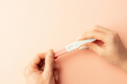 Pregnancy test kit. Female hand hold positive pregnant test with silk ribbon on pink background. Medical healthcare gynecological, pregnancy fertility maternity people concept.