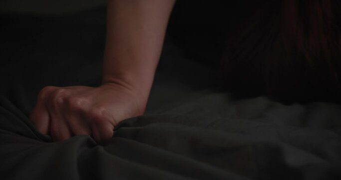 Person's Hand Passionately Gripping A Black Bed Sheet During An Intimate Scene. Close-up
