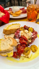 Top view of fresh beef tartare with burrata mozzarella, cocktail tomatoes, toasted white bread and olives. Having a date in the city center in Padua, Veneto, Italy, Europe. Luxury eating