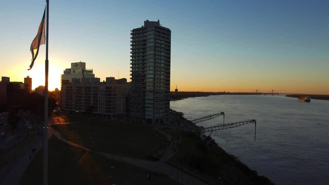 Puerto Norte, Rosario, Argentina: Loading dock in the port of Northern Cordoba used for loading and unloading of goods along the river parana with the view of multi storied buldings during sunset.