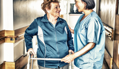 Asian female doctor reassuring mature elderly woman with walker. Two women smiling happy in the...