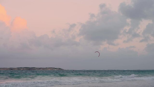 Kitesurfer in the ocean with a strong wind off the coast of a tropical island in the Caribbean before sunset