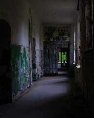 Fototapeta premium 10.05.2022- Oranienburg, Germany: Dark corridor of an abandoned German-Soviet lung hospital. Dilapidated walls, peeling paint, broken glass. Ruined tuberculosis-Sanatorium 