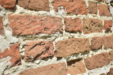 A wall of old, cracked bricks, with a weathered and faded surface. Restored brickwork of an old...